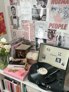 a record player sitting on top of a table next to a vase filled with flowers