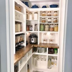 a kitchen pantry with white cabinets and wooden counter tops, black and white tile flooring