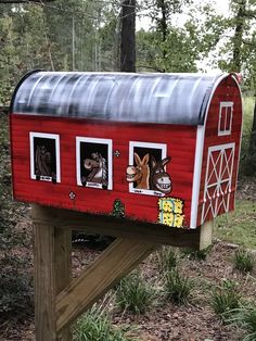 a red painted mailbox with pictures of animals on it's side and windows