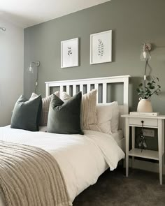 a white bed sitting in a bedroom next to two framed pictures on the wall above it