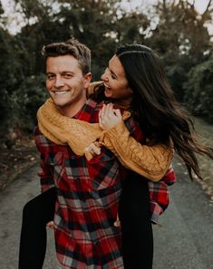 a man carrying a woman on his back while walking down a path in the woods