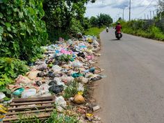 a man riding a motorcycle down a street filled with trash