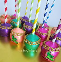 there are many different colored cake pops with chains on them and one has a candle in it