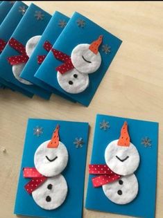 four snowmen made out of felt sitting on top of blue envelopes