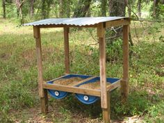 a wooden cart with wheels in the middle of a grassy area next to some trees