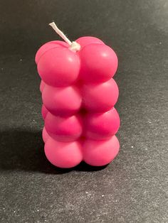 a small pink candle sitting on top of a black table next to a red apple