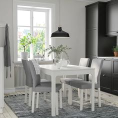 a dining room table with chairs and a potted plant in the corner next to it