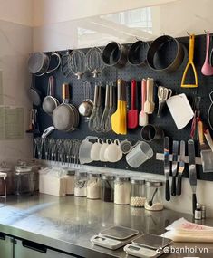 a kitchen with pots, pans and utensils hanging on a pegboard