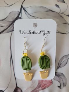 a pair of green and yellow earrings on top of a flowery background with the words wonderlandland gifts written below it