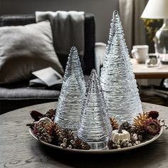 three clear glass trees sitting on top of a wooden table next to a couch in a living room