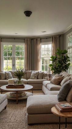 a living room filled with lots of furniture next to two large windows covered in curtains