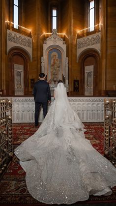 a bride and groom standing in front of the alter at their wedding ceremony, with an ornately decorated altar behind them