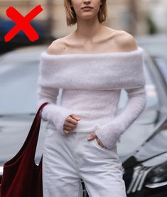 a woman with short hair wearing white pants and off the shoulder sweater is standing in front of a car