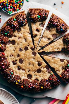 a chocolate chip cookie cake with one slice cut out and sprinkles on the side