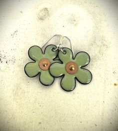 These sweet flower earrings will win you over with their cuteness! These earrings are made from copper flowers that are about 1 inch in diameter.  A center hole was drilled and they were gently shaped concave.  Multiple layers of a pretty lichen green enamel were added and fired in a kiln several times to create a soft, pretty green.  Edges have been left with a slight burnt edge for a more organic feel.  A tiny copper washer and rivet was added to the center. Finally, the earrings were finished with hand-forged ear wires made from sterling silver wire. This listing is for one pair of earrings only.  The 4th photo shows a similar pair of earrings with other earrings in my shop for both size and color comparison. Green Flower-shaped Pierced Earrings, Nickel-free Enamel Flower Earrings Gift, Gift Nickel-free Enamel Flower Earrings, Green Whimsical Flower Shaped Earrings, Green Hypoallergenic Flower-shaped Earrings, Hypoallergenic Green Flower-shaped Earrings, Nickel-free Enamel Flower Earrings, Nickel-free Flower Earrings, Flower-shaped Enamel Flower Earrings For Gift