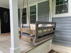 a porch swing with pillows hanging from it's sides on the front porch,