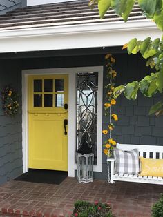 a yellow front door sits next to a white bench