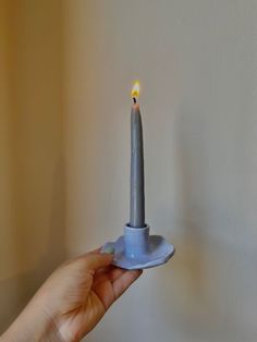 a person holding a small blue candle with a yellow light on it's tip