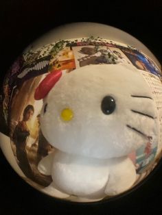 a white hello kitty stuffed animal sitting on top of a black table next to a wall