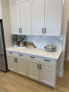 a kitchen with white cabinets and silver appliances