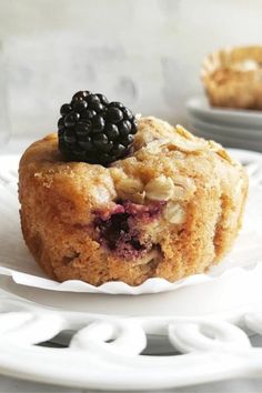 a close up of a muffin on a plate with blackberries and almonds