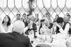 a group of people sitting around a table with wine glasses in front of them,