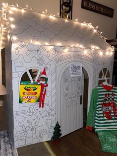 a cardboard house with christmas lights on the front and side walls, decorated like a santa's workshop