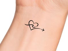 a small tattoo on the wrist of a woman with an airplane flying through the heart