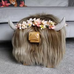 a wig with horns and flowers on it sitting in front of a couch next to a pillow