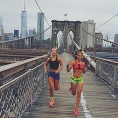 two women running across a bridge in the city