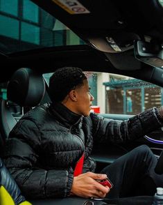 a man sitting in the driver's seat of a car holding a cell phone