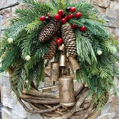 a christmas wreath with bells and pine cones on it is hanging from a brick wall