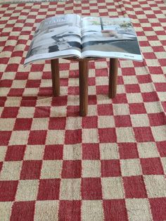 an open book sitting on top of a red and white checkered rug