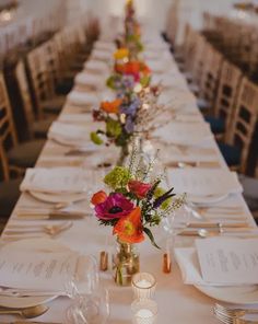 a long table is set with flowers and place settings