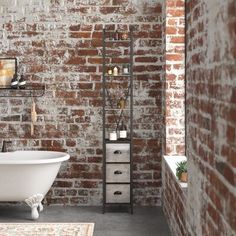 a bath tub sitting next to a brick wall in a room with a rug on the floor