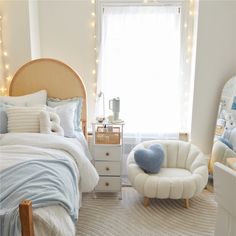 a bedroom decorated in white and blue with lights on the window sill, bedding, and chair