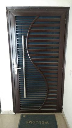 a door with a metal design on it and a welcome mat in front of it