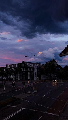 an empty street at dusk with dark clouds in the sky