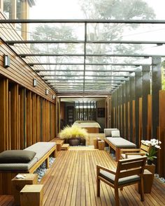 the inside of a house with wood floors and large glass doors on one side, wooden benches to the other