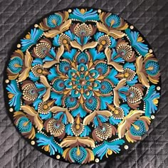 a blue and gold plate sitting on top of a quilted tablecloth covered floor