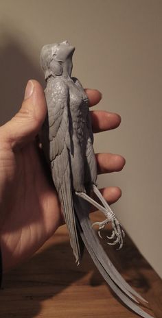 a hand holding a small bird on top of a wooden table