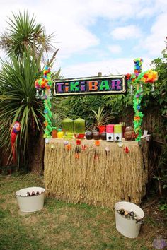 a tiki bar is set up outside in the grass with decorations on it and two buckets full of drinks