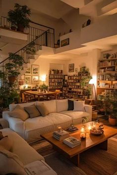 a living room filled with lots of furniture and bookshelves next to a stair case