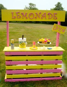 a yellow and pink lemonade stand on grass