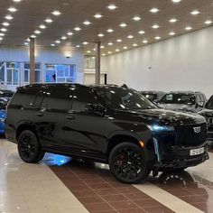 a black suv is parked in a showroom