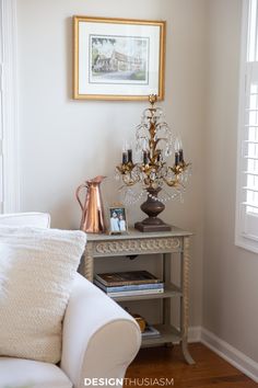 a white couch sitting next to a table with a chandelier on top of it