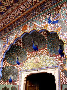 an ornate doorway with peacocks painted on the wall and ceiling above it, in india