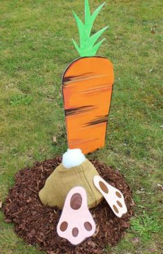 a wooden carrot sitting on top of a pile of dirt next to a hole in the ground