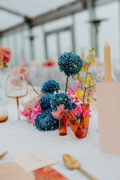 the table is set with blue and pink flowers in glass vases, gold cutlery, and napkins