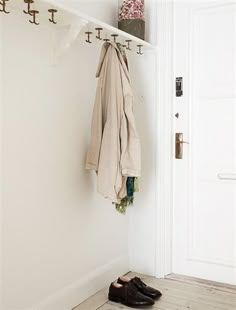 a pair of shoes is sitting on the floor next to a coat rack with coats hanging from it